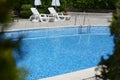 Outdoor swimming pool with handrails and empty sunbeds at resort on sunny day Royalty Free Stock Photo