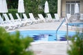 Outdoor swimming pool with handrails and many empty sunbeds at resort on sunny day Royalty Free Stock Photo