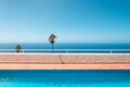 Outdoor swimming pool with ocean view, palm trees and clear blue sky Royalty Free Stock Photo