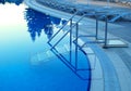 Outdoor swimming pool in-pool ladder with sunbeds in background Royalty Free Stock Photo