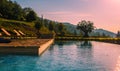 Outdoor swimming pool in Tuscany with pink sunrise sky and an olive tree