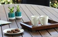 Outdoor table setting with cookies, two white coffee cups, book, flowers