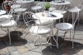 Outdoor terrace of cafe with beautiful white wrought iron chairs and table in sunny summer day.