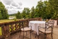 an outdoor terrace with a table and chairs on the river and green trees against the backdrop of concrete railings Royalty Free Stock Photo