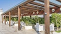 On the outdoor terrace, under a wooden canopy with a glass roof, there are white wicker chairs and tables Royalty Free Stock Photo