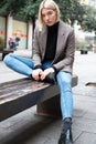 Outdoor urban female portrait. Fashion model. Young woman posing in Milan streets. Beautiful caucasian girl with blond hair sits Royalty Free Stock Photo