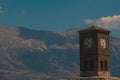 Outdoor view of a clocktower against blue sky and mountain landscape Royalty Free Stock Photo