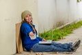 Outdoor view of homeless smiling woman begging on the street in cold autumn weather sitting on the floor with a empty Royalty Free Stock Photo