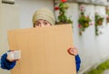 Outdoor view of homeless woman holding up blank cardboard sign Royalty Free Stock Photo