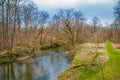 Outdoor view of path inside of the forest covered with green grass and some dry trees close to a small river in Royalty Free Stock Photo