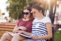 Outdoor view of serious concentrated two schoolgirls reads textbook attentively, try to learm material for lesson, enjoy fresh air Royalty Free Stock Photo