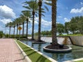 An outdoor view of a water feature at a mall with a line of palm trees