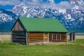 Outdoor view of wooden Cabin with green rooftop on a Golden Grass Prairie against the Grand Teton Mountains, National Royalty Free Stock Photo