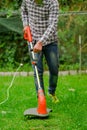 Outdoor view of young worker using a lawn trimmer mower cutting grass in a blurred nature background Royalty Free Stock Photo