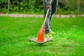 Outdoor view of young worker wearing jeans and using a lawn trimmer mower cutting grass in a blurred nature background Royalty Free Stock Photo