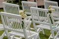 Outdoor wedding ceremony, chairs decorated with flowers and ribbons stand in rows on the grass