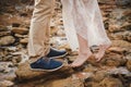 Outdoor wedding ceremony, close up of young woman feet standing barefoot on stones in front of mans feet wearing dark blue shoes