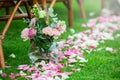 Outdoor wedding ceremony decoration setup. Path with petals, chairs decorated with colorful ribbons, white arch