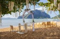 Outdoor wedding ceremony on tropical beach. Wedding decoration under palm trees. Exotic wedding. Wedding floral arch and chairs. Royalty Free Stock Photo