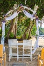 Outdoor wedding ceremony on tropical beach. Wedding decoration under palm trees. Exotic wedding. Wedding floral arch and chairs. Royalty Free Stock Photo