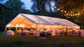 Outdoor wedding reception at twilight with illuminated tent and guests