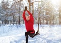 Outdoor winter fitness concept. Sporty senior man training with TRX resistance straps at snowy forest Royalty Free Stock Photo