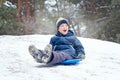 Boy sledding in a snowy forest. Outdoor winter fun for Christmas vacation. Royalty Free Stock Photo