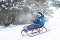 Boy sledding in a snowy forest. Outdoor winter fun for Christmas vacation. Royalty Free Stock Photo