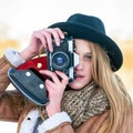 Outdoor winter lifestyle portrait of pretty blonde woman with retro camera Royalty Free Stock Photo