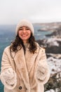 Outdoor winter portrait of elegant happy smiling beige hat, light faux fur coat holding heart sparkler, posing against