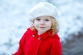 Outdoor winter portrait of little cute toddler girl in red coat and white fashion hat barret. Healthy happy baby child Royalty Free Stock Photo