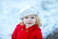 Outdoor winter portrait of little cute toddler girl in red coat and white fashion hat barret. Healthy happy baby child Royalty Free Stock Photo