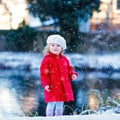 Outdoor winter portrait of little cute toddler girl in red coat and white fashion hat barret. Healthy happy baby child Royalty Free Stock Photo