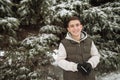 Outdoor winter portrait for young handsome man. Beautiful teenager in his jacket and vest posing on a city street, background of f