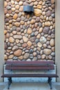 Outdoor Wood Bench by Rock Wall with light sconce Royalty Free Stock Photo