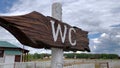 An outdoor wooden arrow signboard WC, public restroom sign in a countryside park