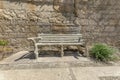 Outdoor wooden bench against rough stone wall viewed on a sunny day Royalty Free Stock Photo