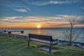 Outdoor wooden bench facing the Oresund Strait with a sunset over the massive Oresund Bridge Oresundsbron in the Baltic Sea