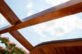 Outdoor wooden pergola, line of wood in detail, Persian silk tree fragment and blue sky on background