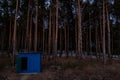 An outdoor wooden toilet stands in a dark forest against the background of tall coniferous trees Royalty Free Stock Photo