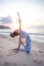 Outdoor yoga on the beach. Young woman practicing variation of Ushtrasana Camel Pose kneeling back bending asana. Flexible spine