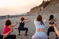 Outdoor yoga and fitness. Back view of group adult fit women are training with dumbbells on pebble beach. Concept of Royalty Free Stock Photo