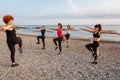 Outdoor yoga and fitness. View of group of athletic Caucasian adult women are training on pebble beach. Concept of Royalty Free Stock Photo