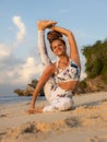 Outdoor yoga practice near the ocean. Attractive woman practicing Eka Pada Sirsasana, Foot-behind-the-Head Pose. Flexible healthy Royalty Free Stock Photo