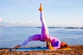 Outdoor yoga practice. Attractive woman practicing variation of Setu Bandhasana, Shoulder supported bridge pose with one leg up. Royalty Free Stock Photo