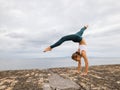 Outdoor yoga practice near the ocean. Caucasian woman practicing Adho Mukha Vrksasana. Yoga Handstand is an inverted asana. Royalty Free Stock Photo