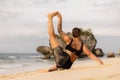 Outdoor yoga practice near the ocean. Caucasian woman practicing Eka Pada Sirsasana, Foot-behind-the-Head Pose. Flexible healthy Royalty Free Stock Photo