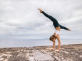 Outdoor yoga practice near the ocean. Young woman practicing Adho Mukha Vrksasana. Yoga Handstand is an inverted asana. Beautiful Royalty Free Stock Photo