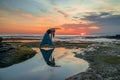 Outdoor yoga practice. Young woman practicing Trikonasana, Triangle Pose. Standing asana. Amazing water reflection. Tanah Lot Royalty Free Stock Photo