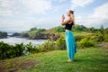 Outdoor yoga practice. Young woman standing on the grass. Hands in namaste mudra, closed eyes. Tanah Lot temple, Bali Royalty Free Stock Photo